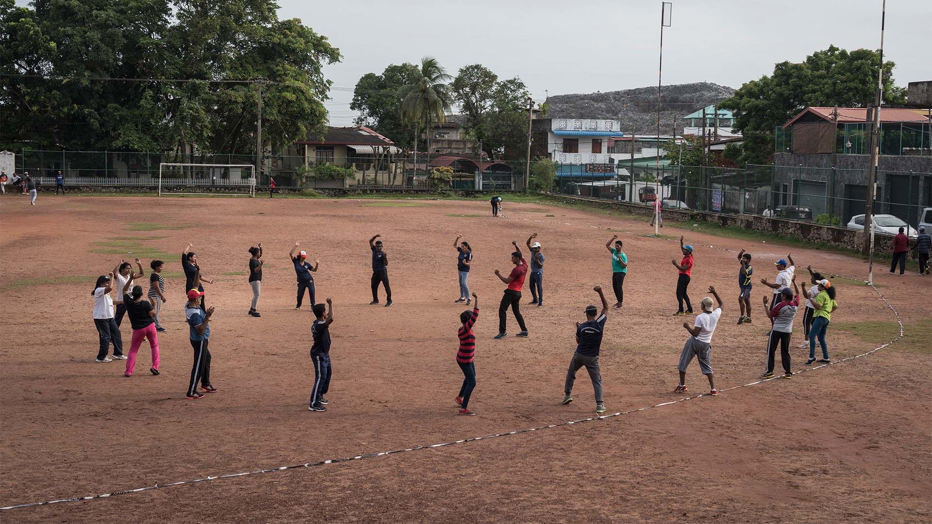 Photo 3 A group of about 20 are standing in a large circle on an outdoor football field doing aerobics.