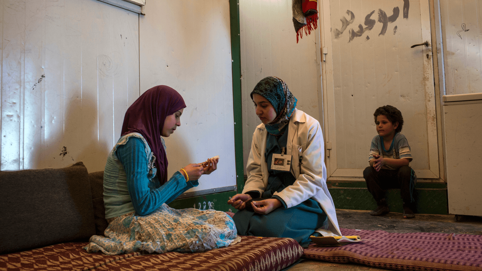 Photo of a female healthcare worker showing a Syrian teenager how to administer her insulin shot.