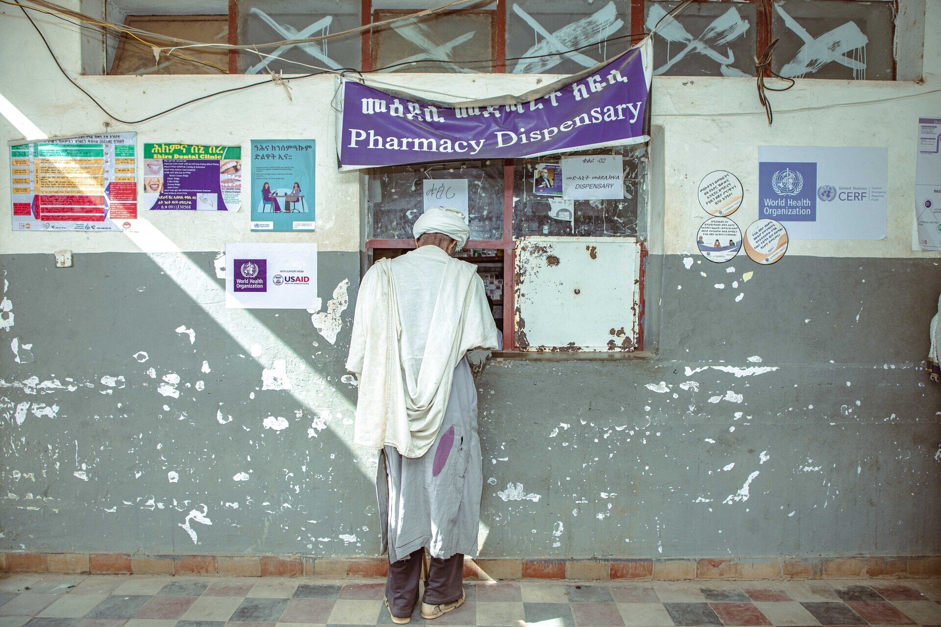 Man in front of the Pharmacy Dispensary in damaged hospital
