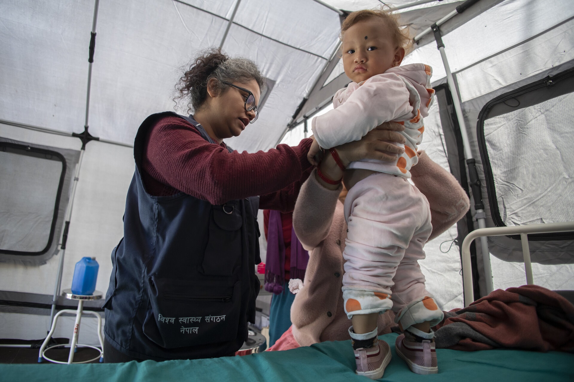 Field Medical Officer from WHO Nepal inspecting child for suspected measles case