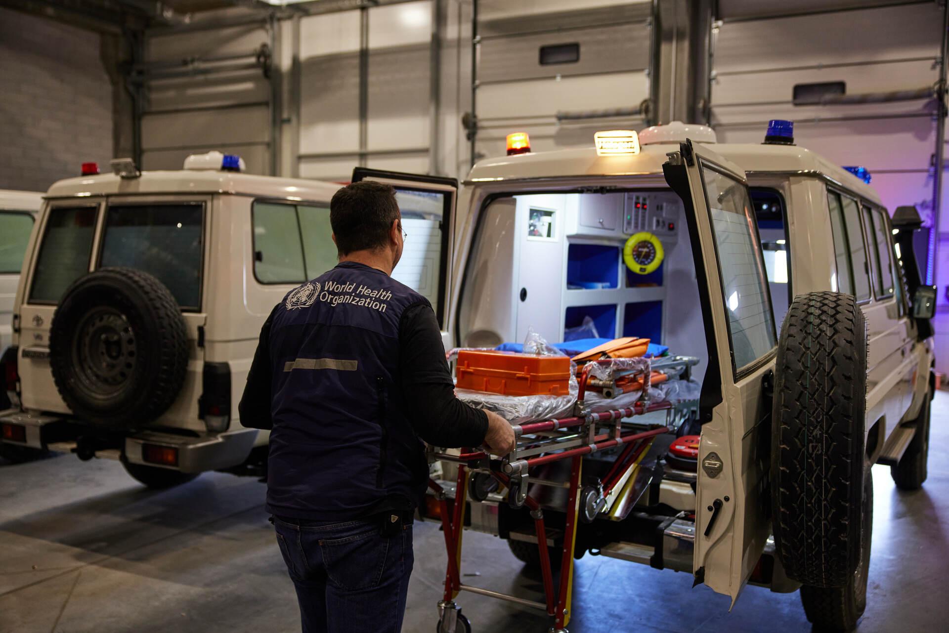 A male WHO staff loads an ambulance inside a warehouse