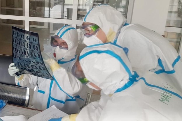 An Emergency Medical Team dressed in personal protective equipment (PPE) are examining a x-ray image.