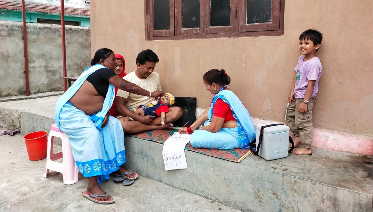 Female Community Health Volunteers recording and administering vaccine for an infant in rural Nepal and maintaining the records to support SDGs and UHC monitoring in communities.