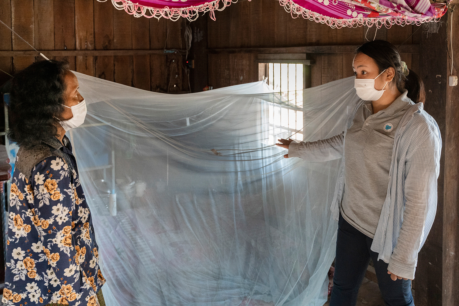 Woman inspects a mosquito net at a house of a recovered malaria patient in a village in Cambodia.