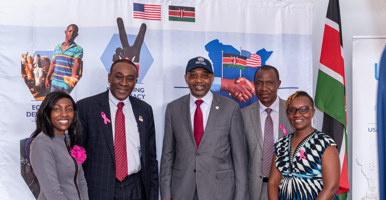 A group of five people standing in front of a banner