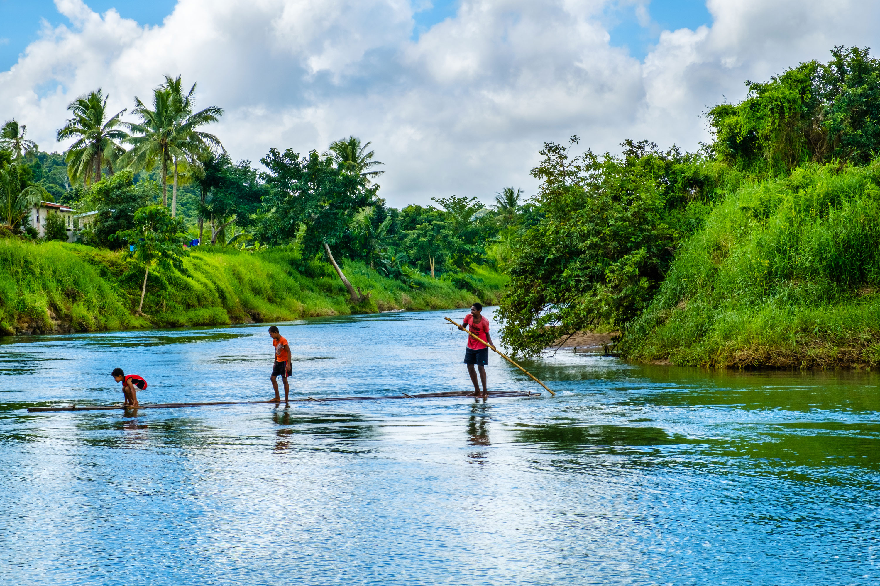 Three men crossing a rive on a raft