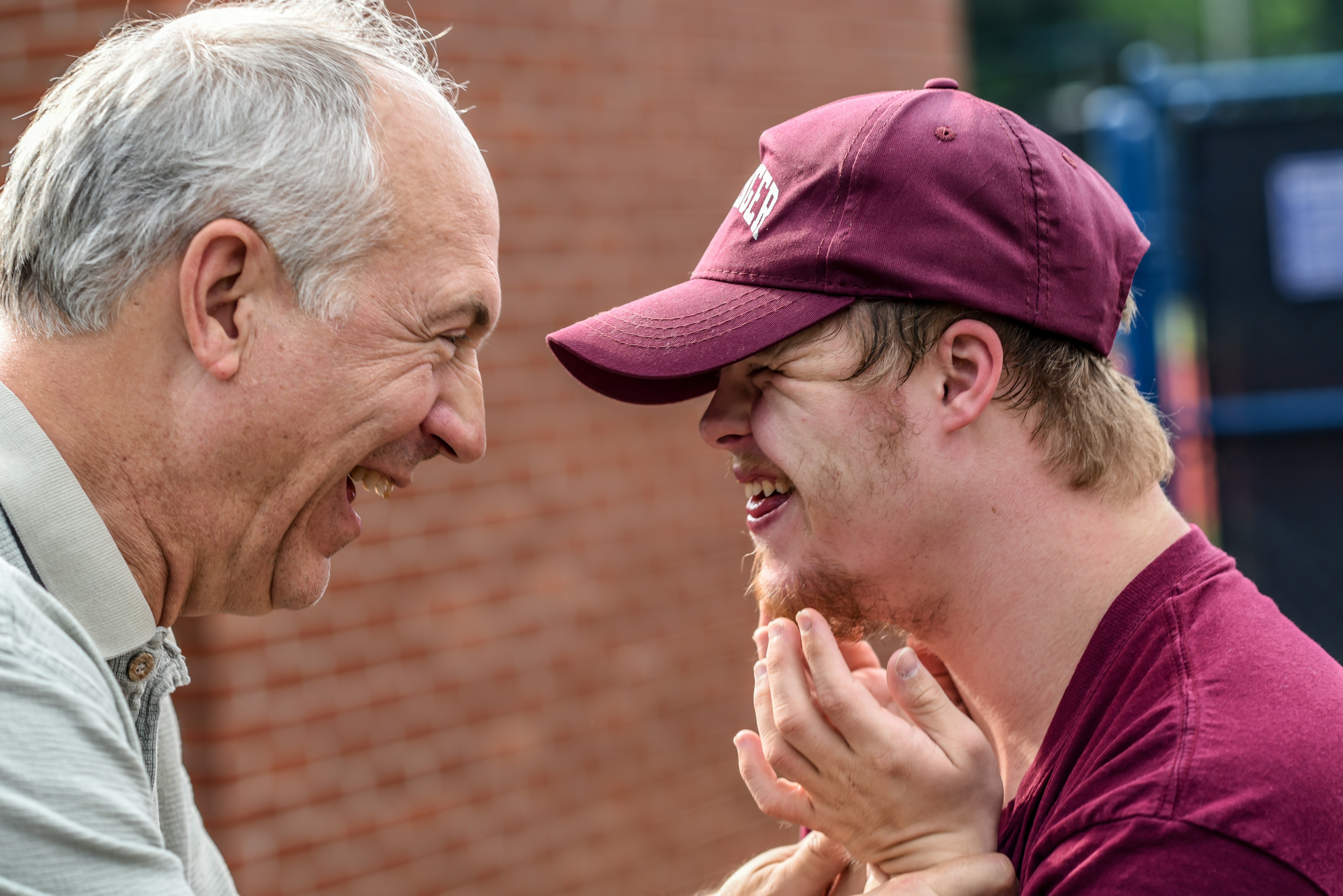 An older man and a younger man with Down Syndrome An older man and a younger man with Down Syndrome are looking at each other, laughing, conveying the sense that social connection should challenge and transcend boundaries.