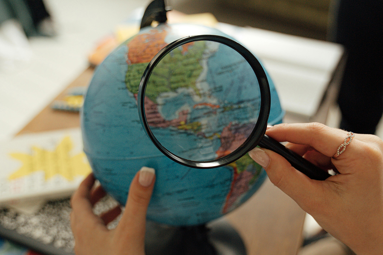 A magnifying glass focussed on a globe, conveying the abstract idea of conducting global research on social isolation and loneliness.