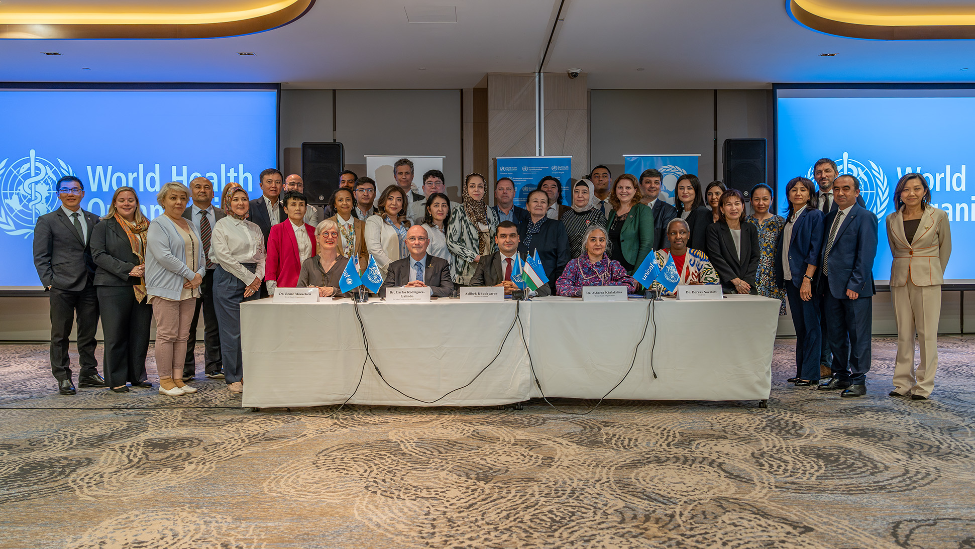 Global platform community of practice A group of people sitting and standing behind a table posing for the photograph.
