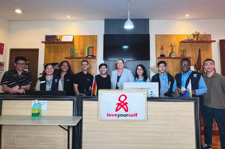 Group of people standing behind desks in a room