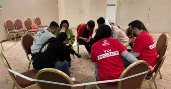 A diverse group of individuals seated in a circle, engaged in discussion and sharing ideas in a collaborative setting.
