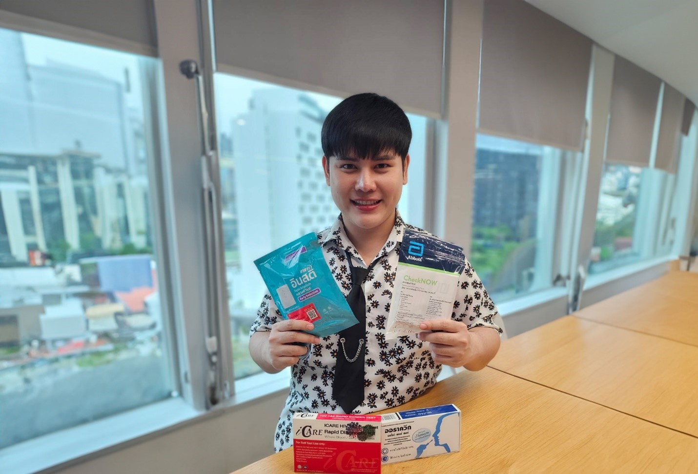 Young man looking into the camera and holding packages of HIV self-tests.
