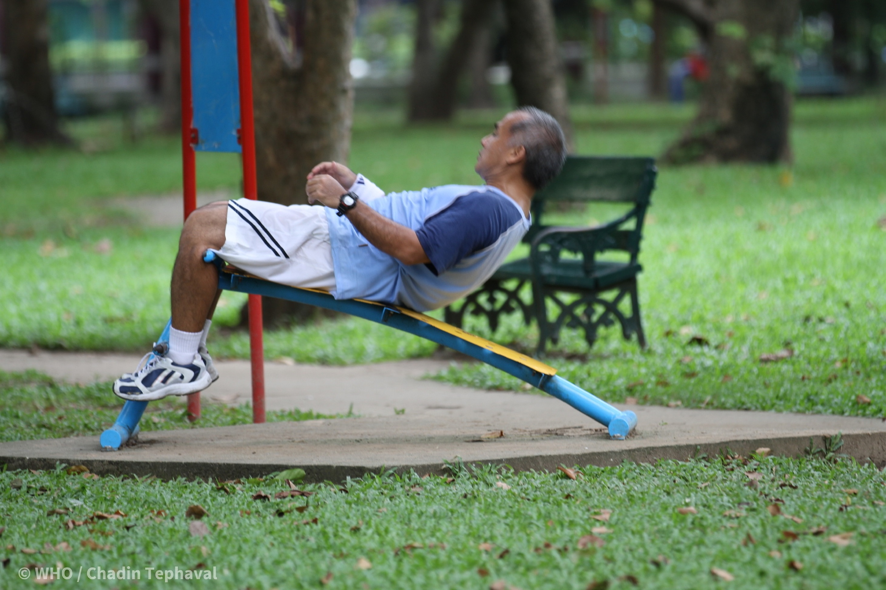 An old man exercising in the park.
