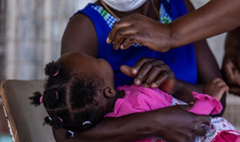 A baby girl receives an oral vaccine