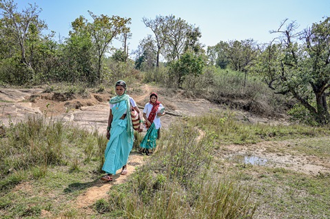 Two women health workers are walking in a country landscape