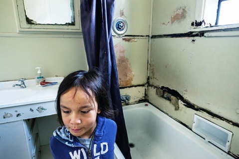 A girl in a bathroom with mold on the walls