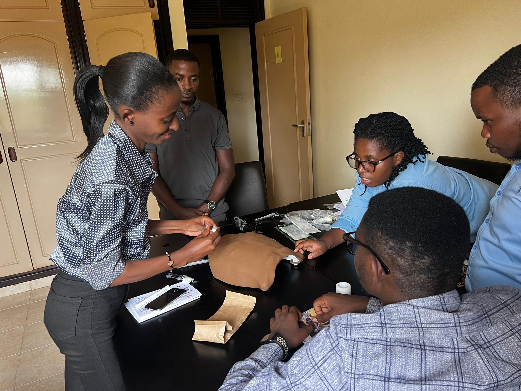 A group of learners in Rwanda practice an emergency clinical skill on a mannequin