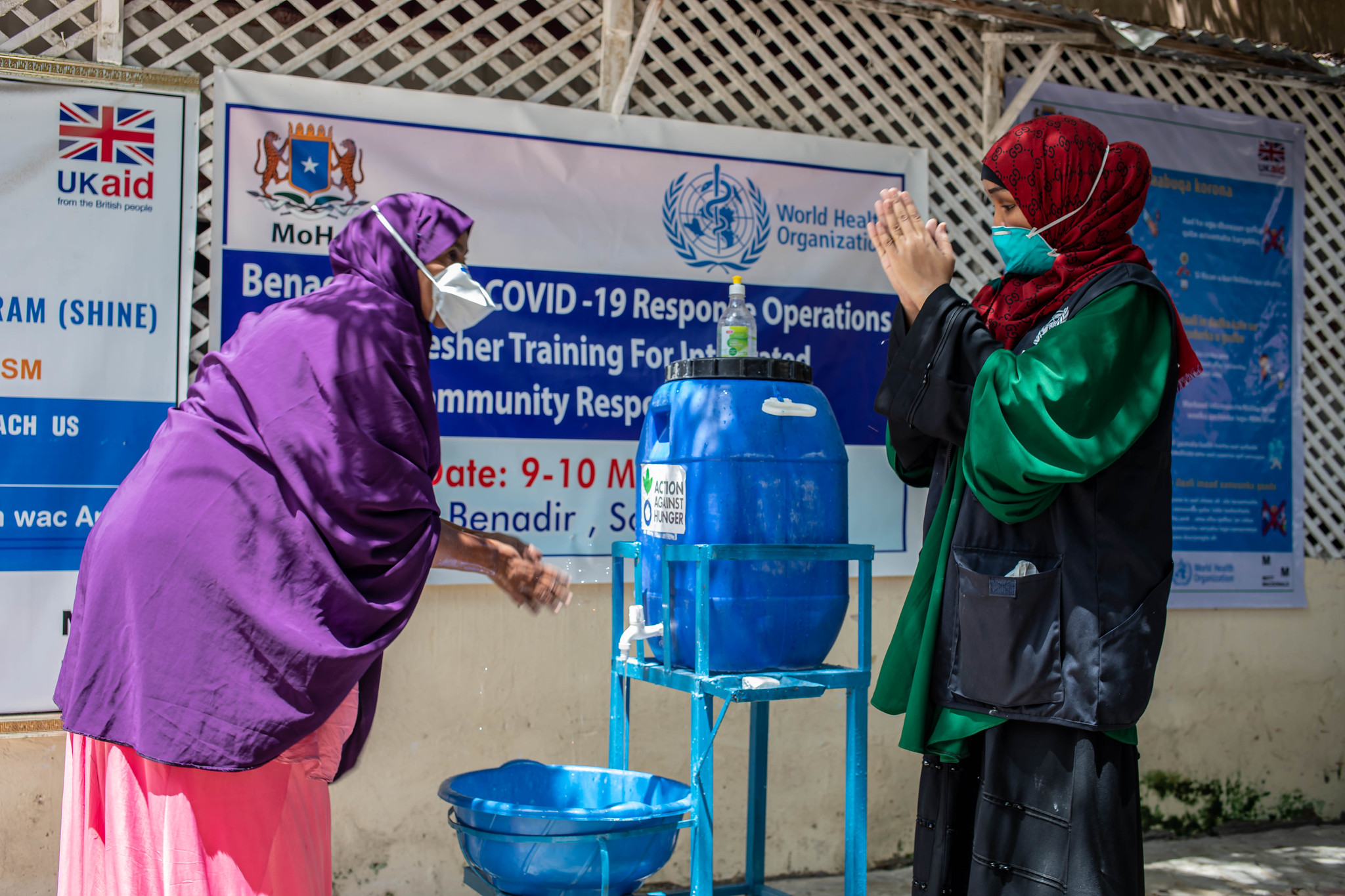 Two women washing their hands at Webari Health Facility in Benaadir Region, Somalia.