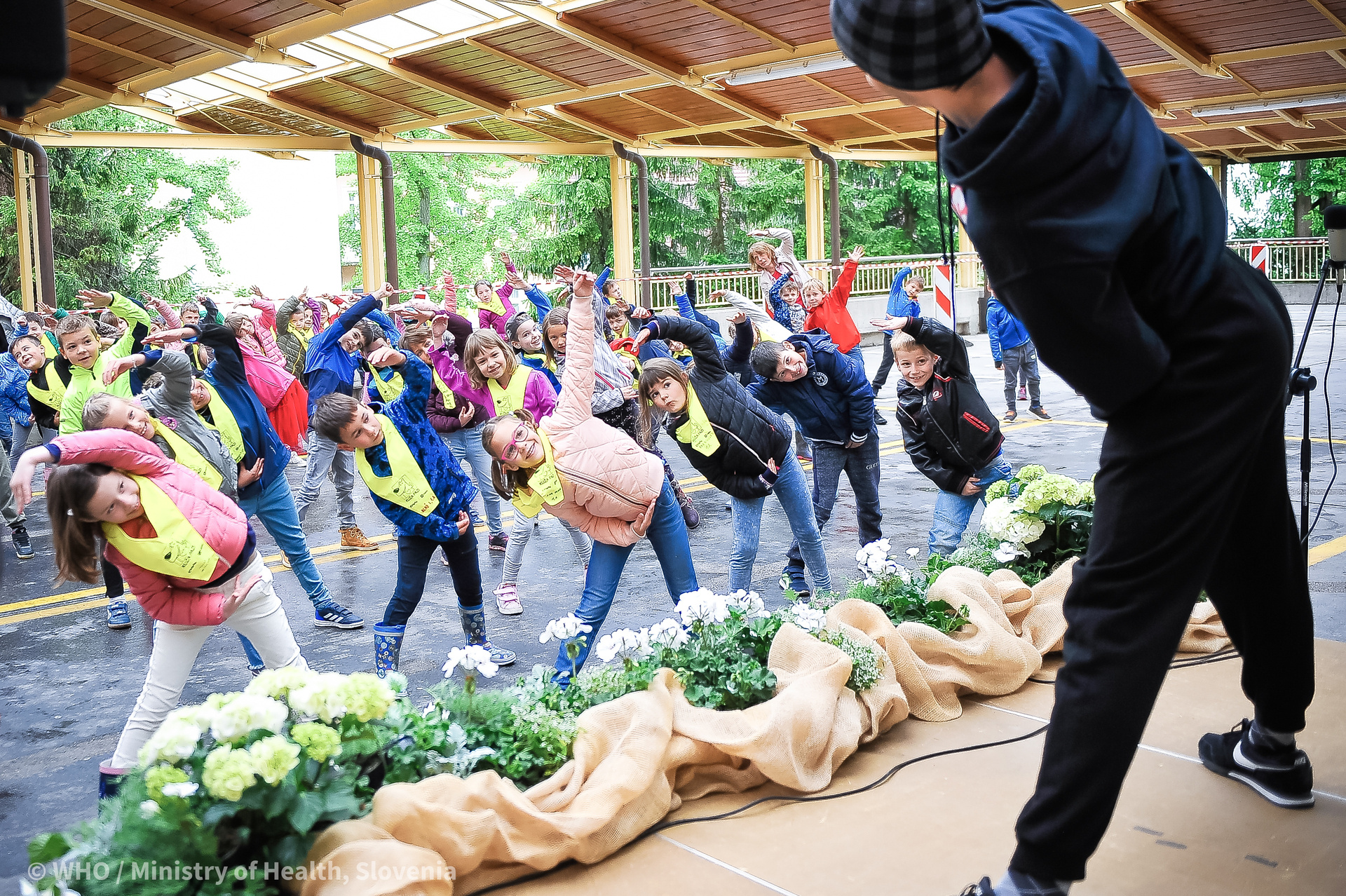 An instructor guiding adolescents in exercise at an outdoor event at a community health center.