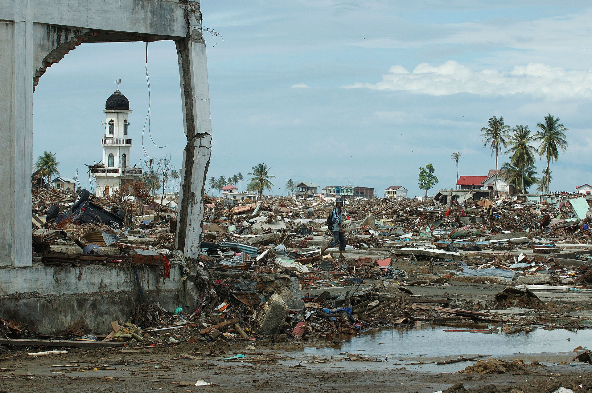 A man picks his way through the wholesale destruction wrought by the tsunami in downtown Banda Aceh. A single minaret from a mosque remains standing amidst the ruins.