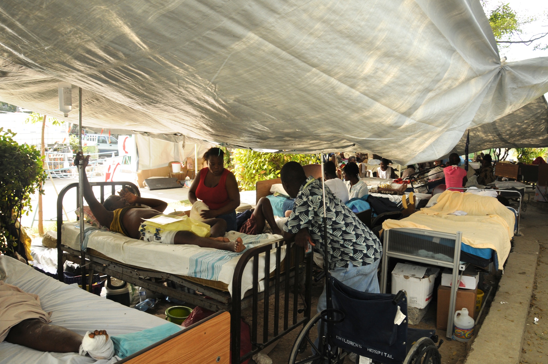 A field hospital tent. Patients in beds. A wheelchair at the front.