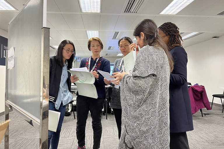 Five participants standing up holding documents