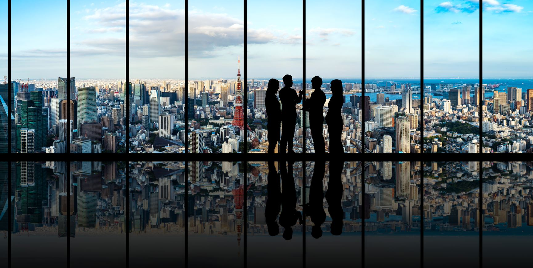4 people standing by a big window with a view of Tokyo in the background
