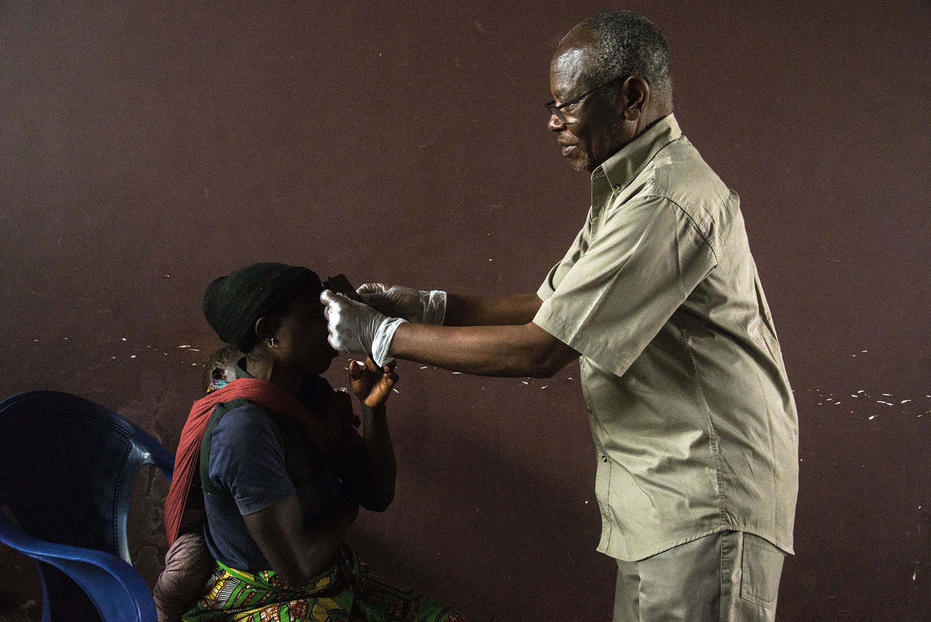 service-delivery A health worker helping a child using an occluder to cover its eye and assess visual acuity