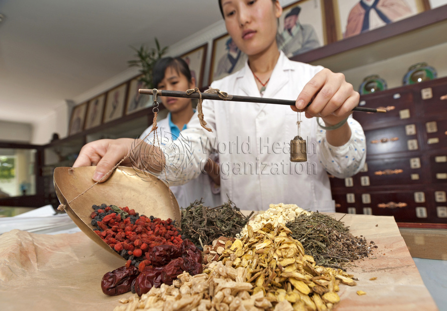 A Chinese staff puts together a combination of herbs for a prescription at a TCM clinic in Simao. Yunnan Province, China. 19 May 2010