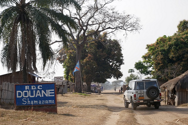 A jeep drives down a dirt road to cross the border of the Democratic Republic of the Congo.