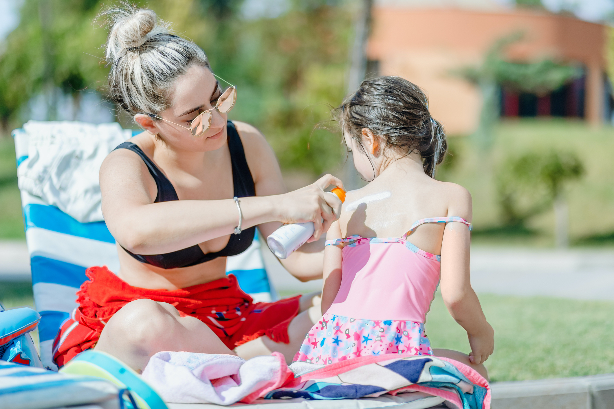 Mother applying suntan lotion on daughter shoulder