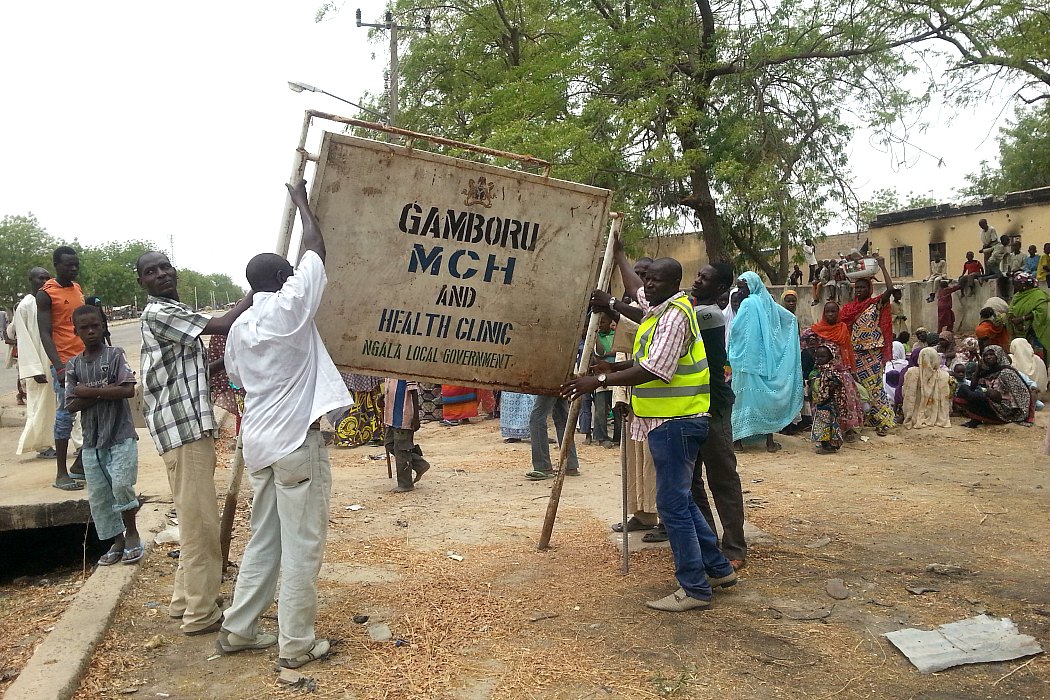 People raising a health clinic sign, eastern Nigeria, 2016.