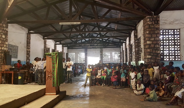 A community gathers at a central meeting place indoors. 