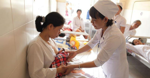 Una enfermera ayuda a una madre joven a amamantar en Viet Nam.