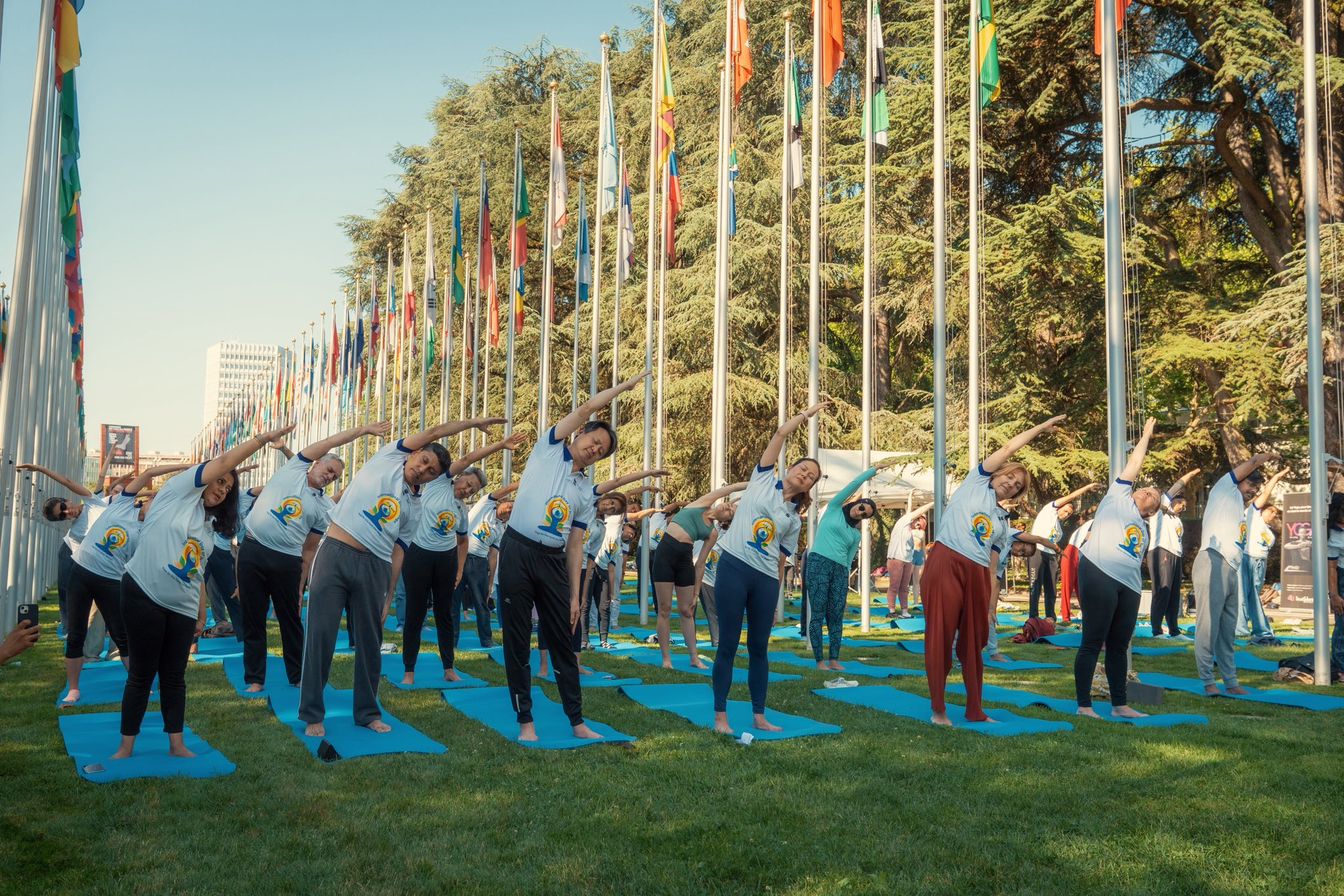 People on yoga mats doing a side stretch on the lawns of UN Palais in Geneva, Switzerland