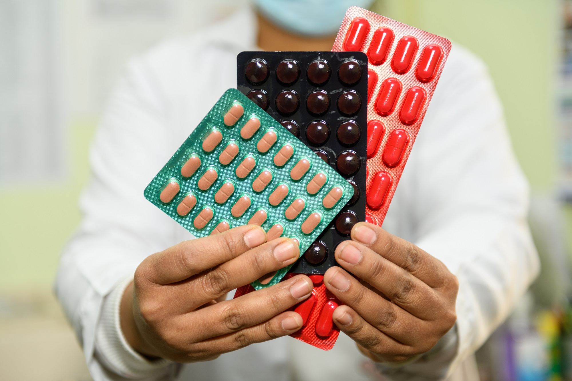 A healthcare worker shows some of the many medications a drug-resistant tuberculosis patient must take for 18 months or more