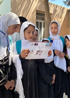 A group of young women and girls one is holding a flyer.