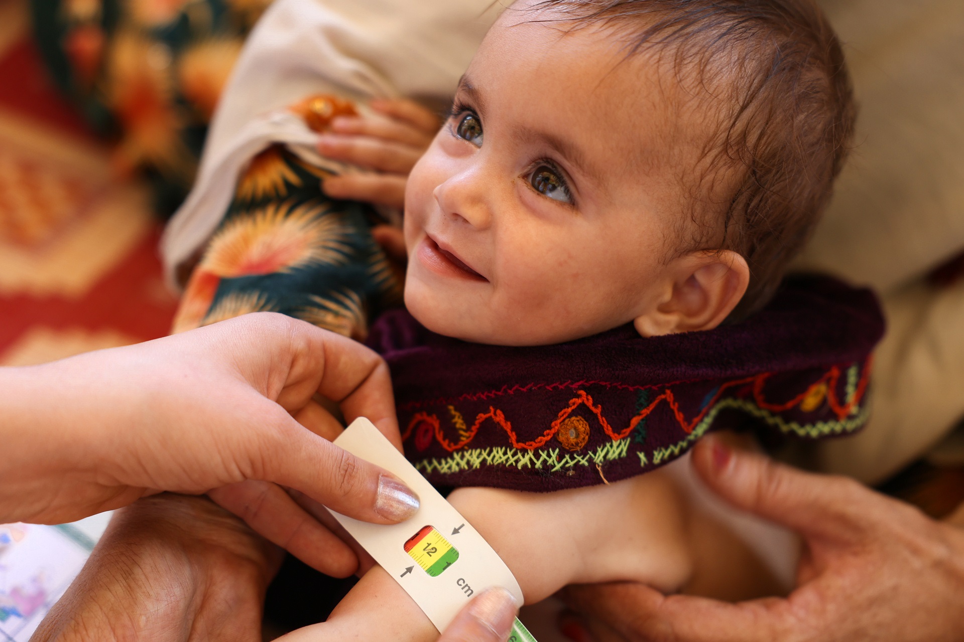 WHE 2025 Appeal Impact in 2024 Afghanistan A health worker is measuring a small child's upper arm.
