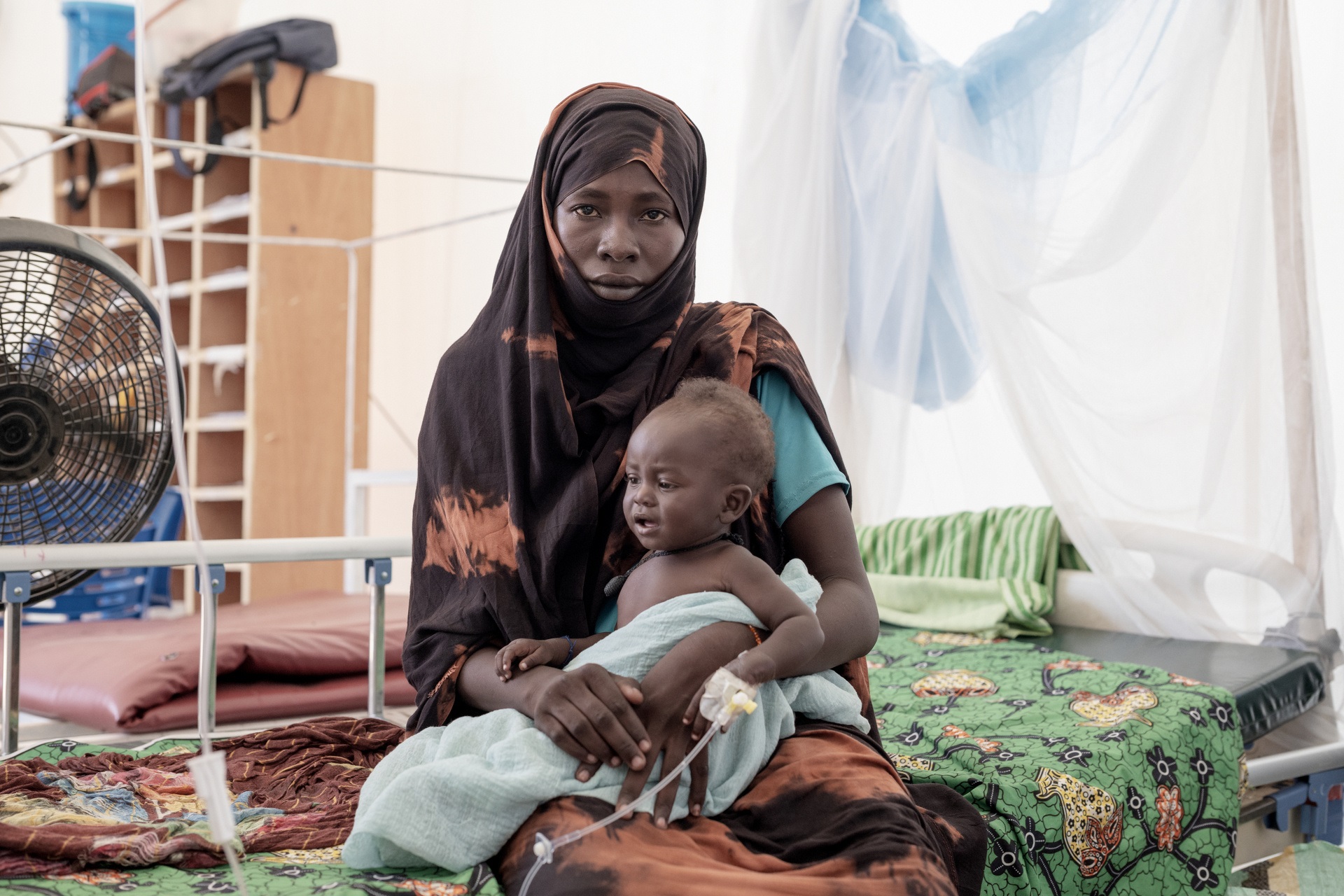WHE 2025 Appeal Impact in 2024 Sudan and South Sudan A woman sitting on a hospital bed holding a baby on her lap.