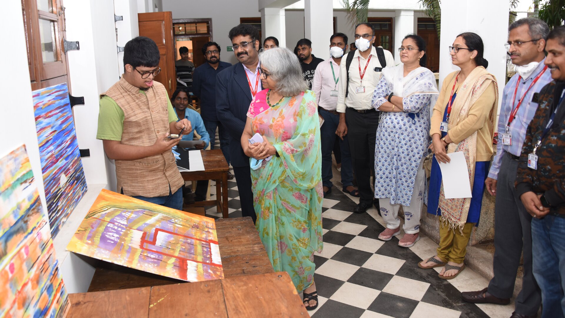 People gathered around a young artist and his paintings.
