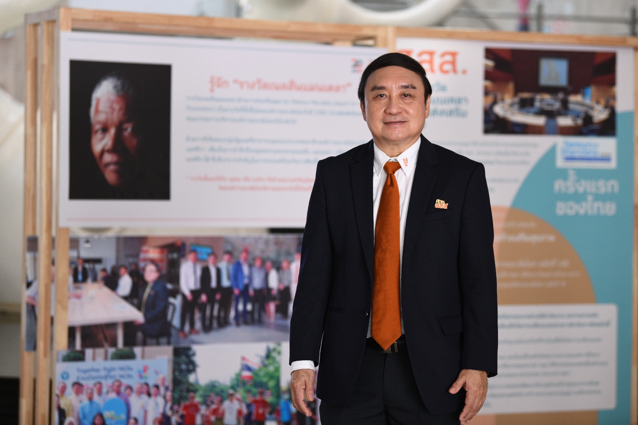 Dr Supreda Adulyanon, CEO of ThaiHealth, in front of an information board about ThaiHealth.
