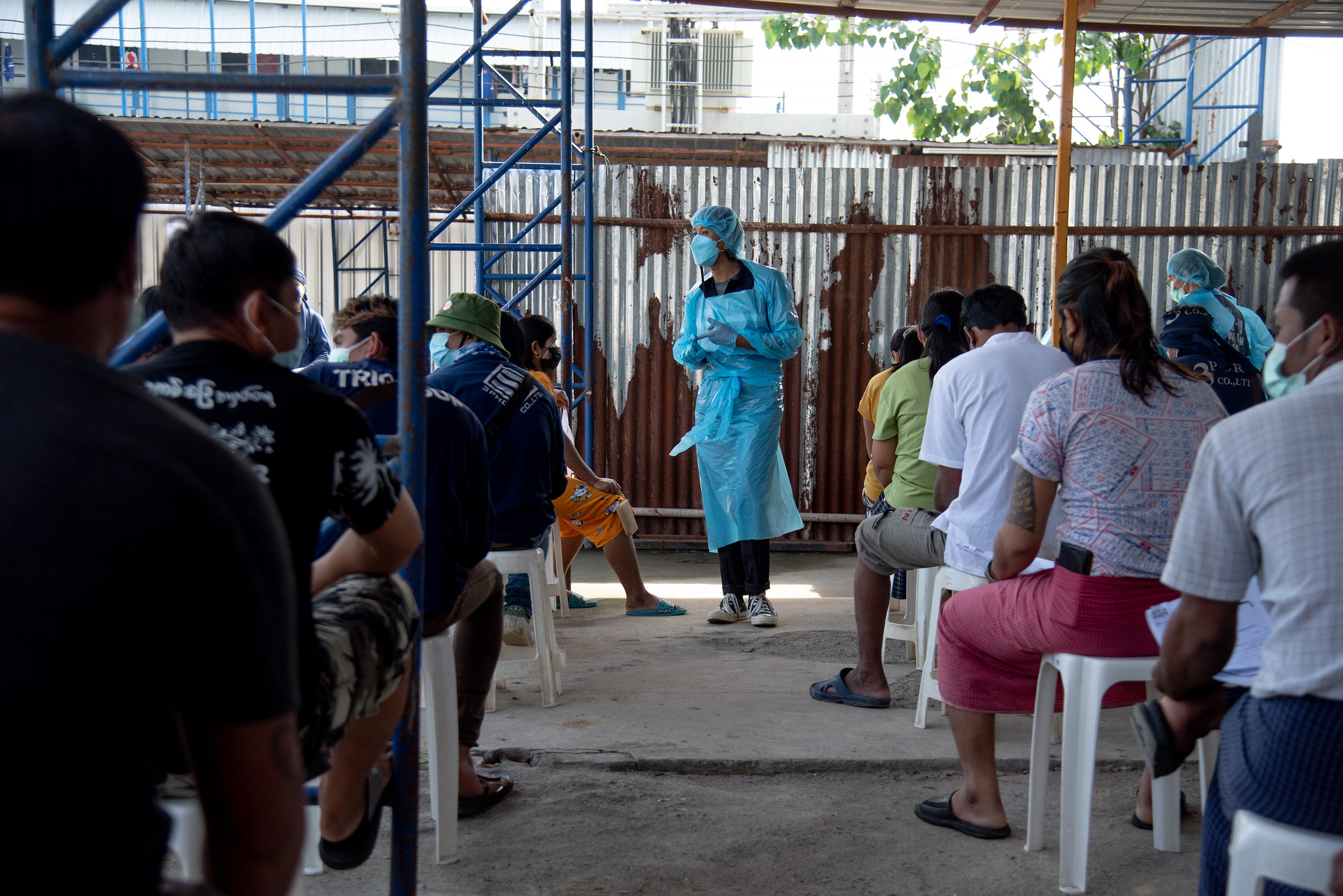 Kyan Thet Khaint, a migrant volunteer, gives COVID-19 information to migrant workers during the waiting time at a migrant labour campsite in Bang Sue, Bangkok – 31st October 2021