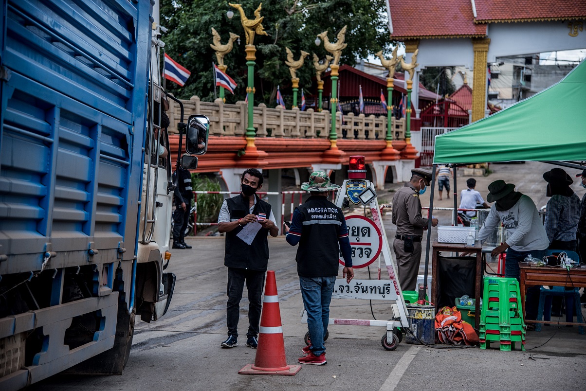 Immigration officers check the forms of a Thai truck carrying goods into Cambodia, crossing at Thailand’s Baan Laem checkpoint on 29 May 2020. Trucks crossing the border are sprayed with disinfectant to prevent the spread of the novel coronavirus