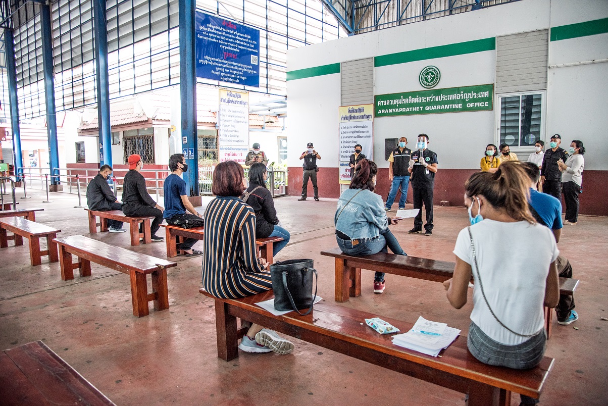 A border health officer tells a group of Thai travelers at Thailand’s Klong Luek border checkpoint on 28 May 2020 how to guard against getting COVID-19. The group had just crossed back home from Cambodia
