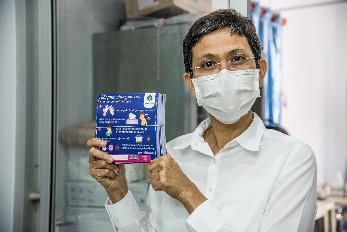 A WHO Thailand officer, Aree Moungsookjareoun, shows flyers on COVID-19 prevention that WHO helped produce. 