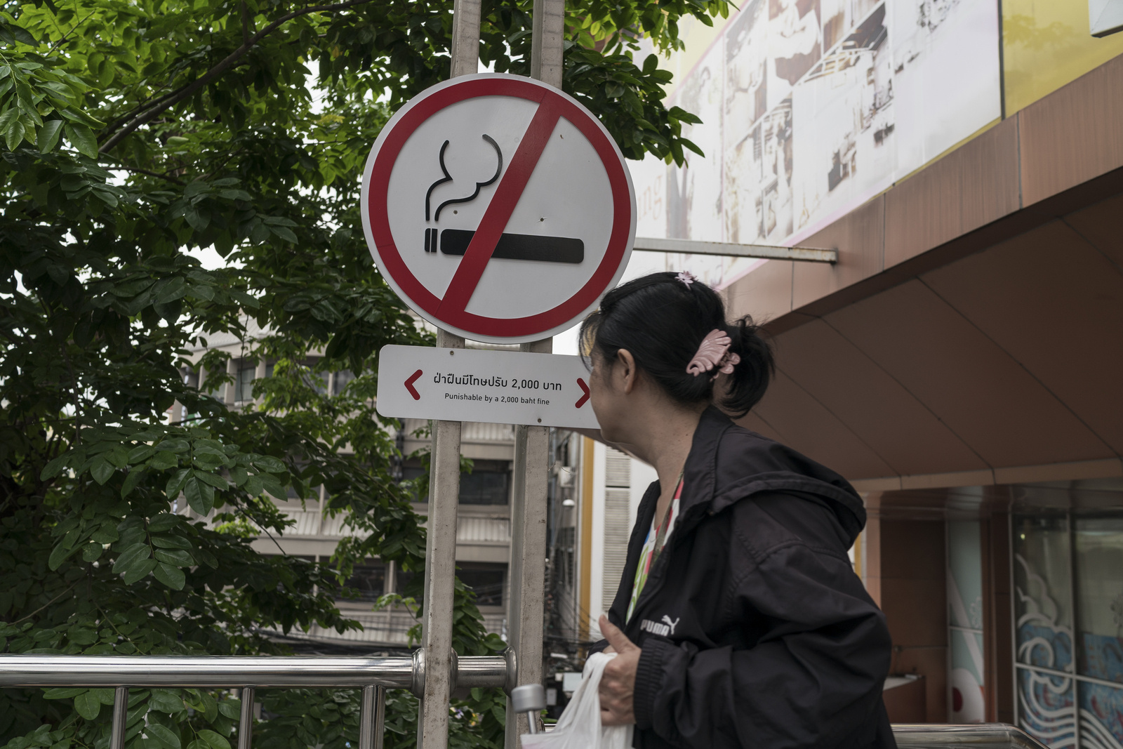 Una mujer pasa junto a una señal que prohíbe fumar en un centro comercial de Bangkok (Tailandia).