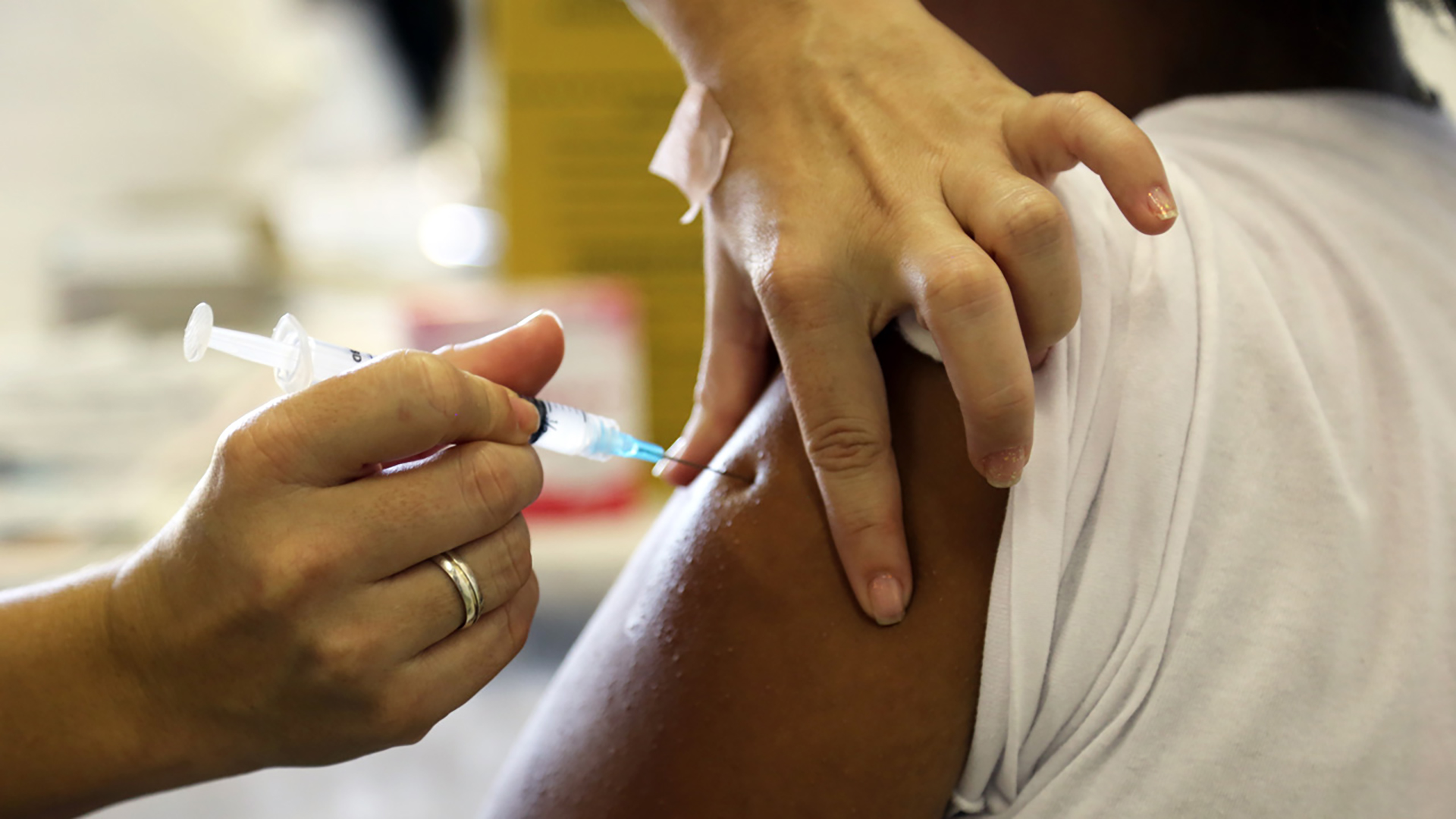 A health worker vaccinating a young woman