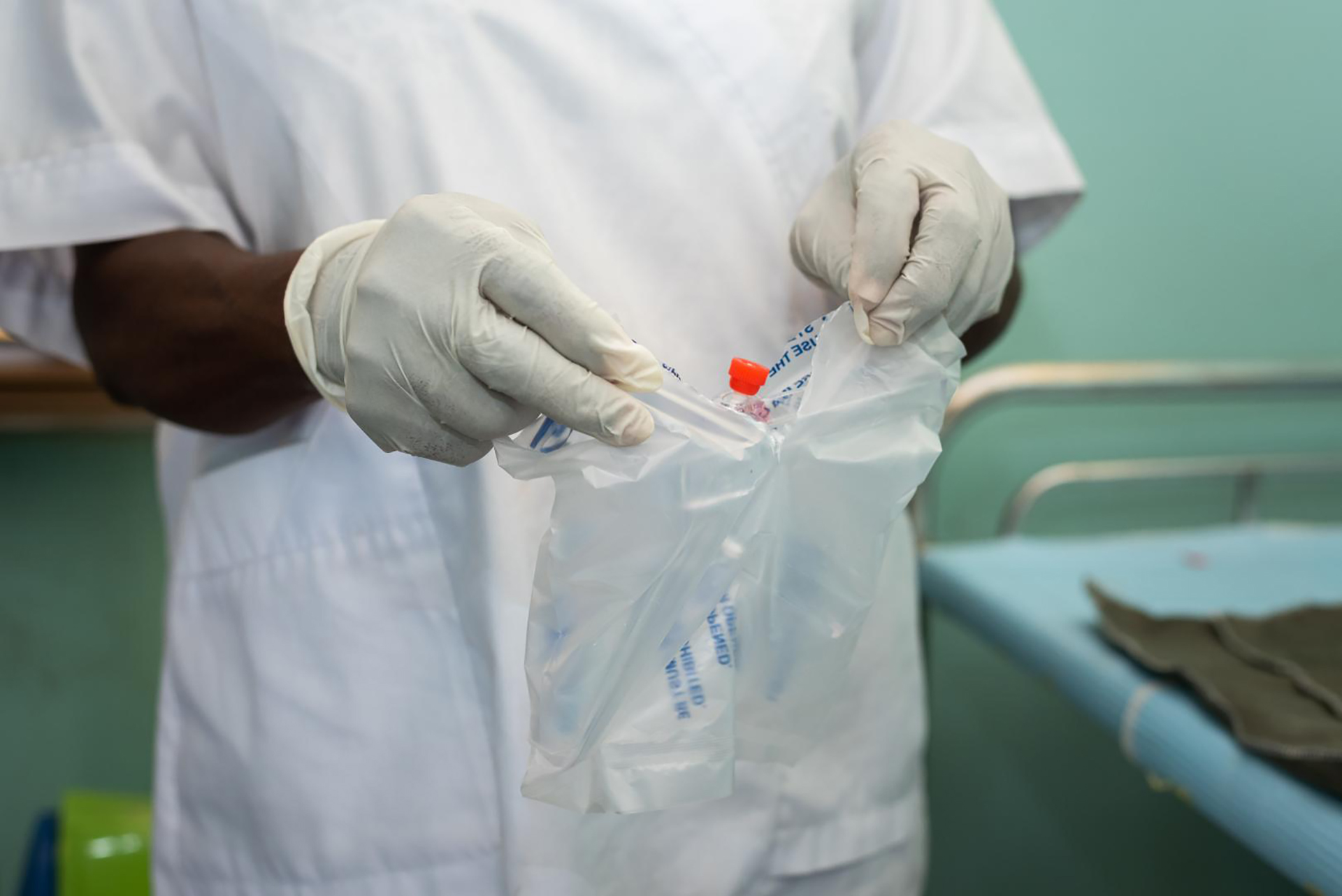 A health worker wearing gloves holding a protective bag