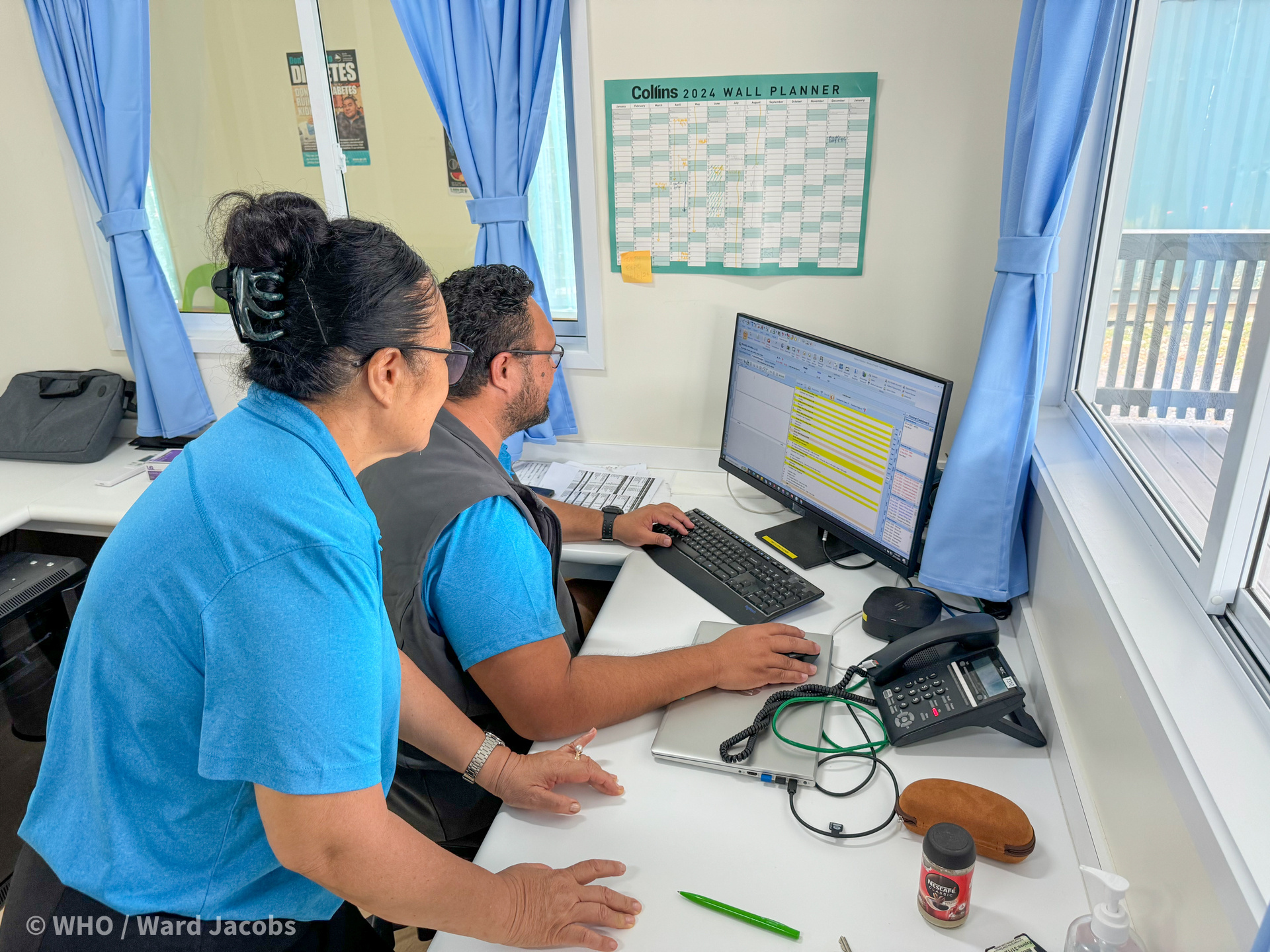 Two health workers looking at the patient file on computer