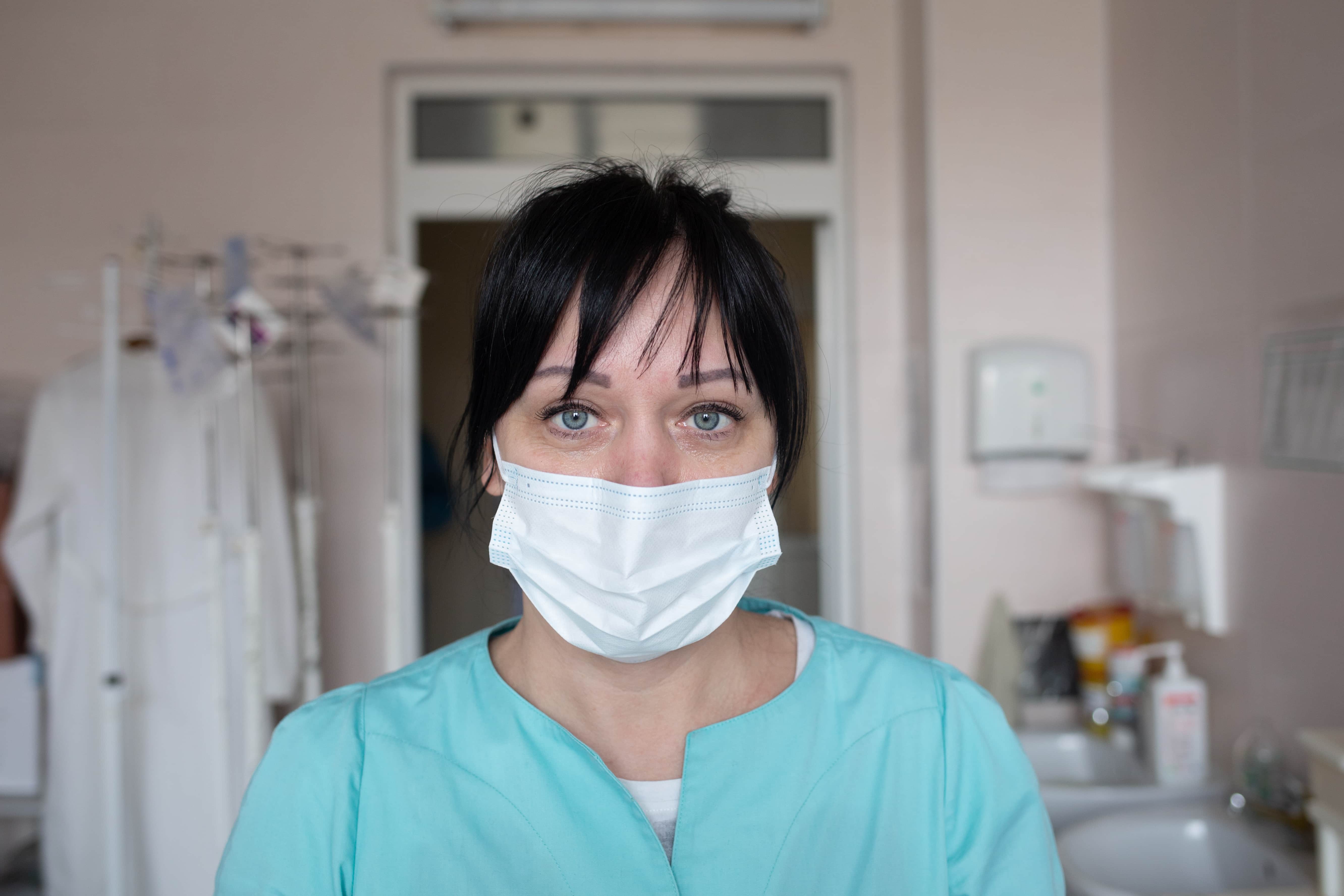 Nurse Inna Portrait photo of a female nurse in a health care setting, wearing hospital attire and a face mask.